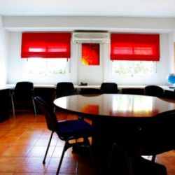 Sala interior con mesa grande y mesas con sillas a los lados