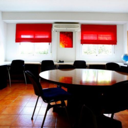 Sala interior con mesa grande y mesas con sillas a los lados