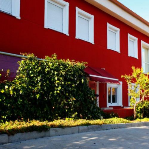 Fachada del edifico en color rojo con ventanas en blanco